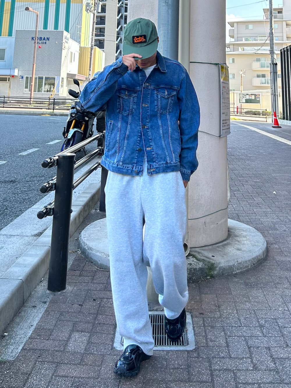 グレー系のスウェットパンツ、ブルー系のデニムジャケット、ブラック系のスニーカーを着用したメンズの秋コーディネートの2枚目の写真