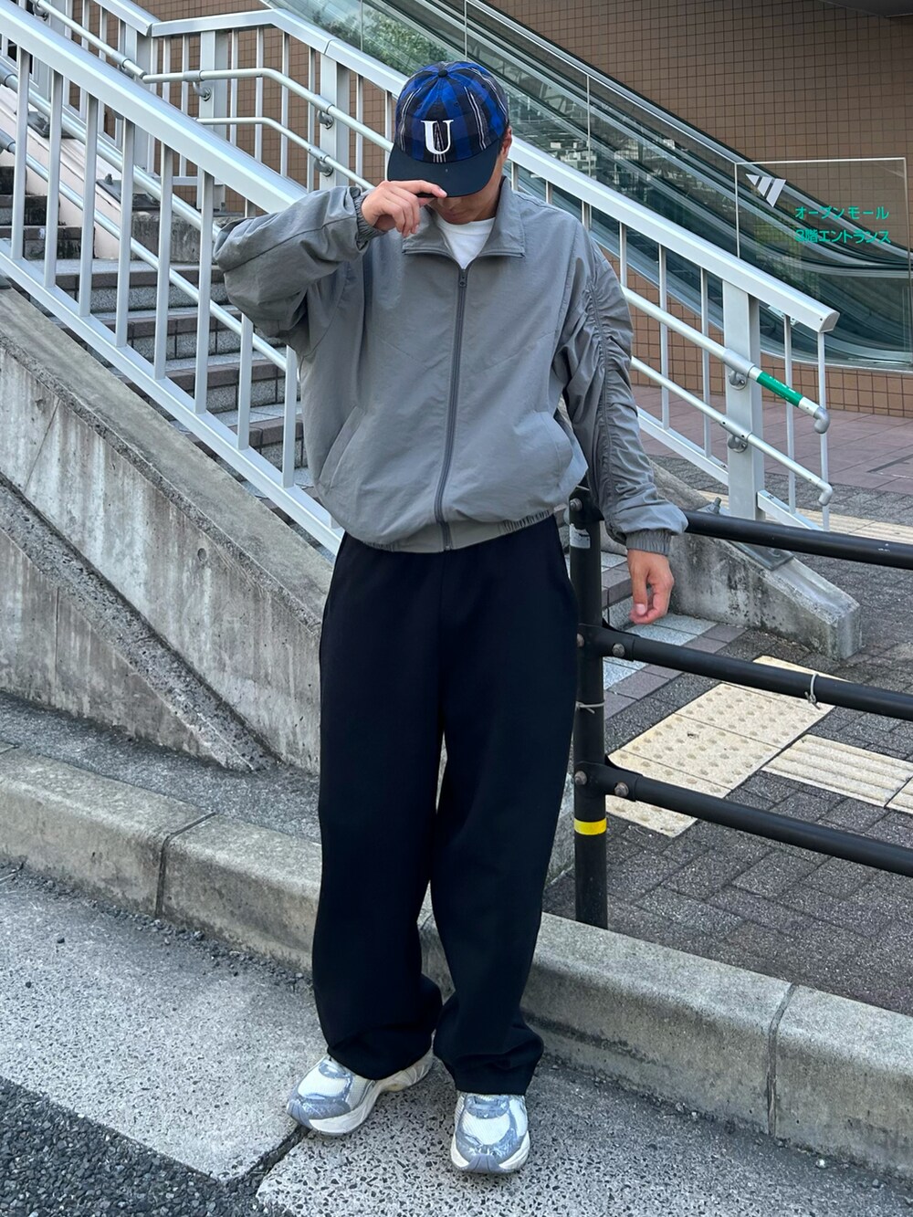 グレー系のブルゾン、シルバー系のスニーカー、ブラック系のスウェットパンツを着用したメンズの秋コーディネートの2枚目の写真