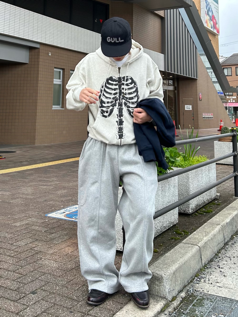 グレー系のパーカー、グレー系のスウェットパンツ、ブラウン系のローファーを着用したメンズの春コーディネートの2枚目の写真