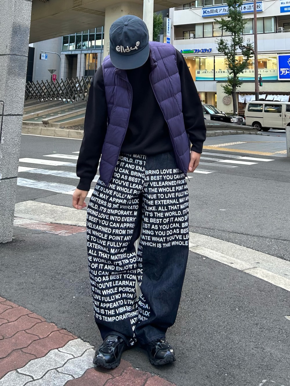 ブルー系のデニムパンツ、パープル系のダウンベスト、ブラック系のスニーカーを着用したメンズの冬コーディネートの2枚目の写真