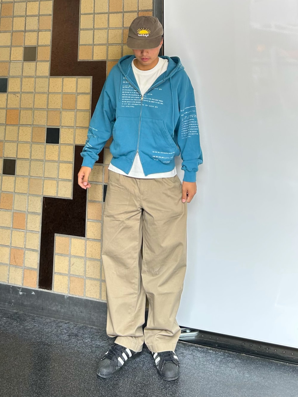 ブルー系のパーカー、ベージュ系のデニムパンツ、ブラック系のスニーカーを着用したメンズの秋コーディネートの2枚目の写真