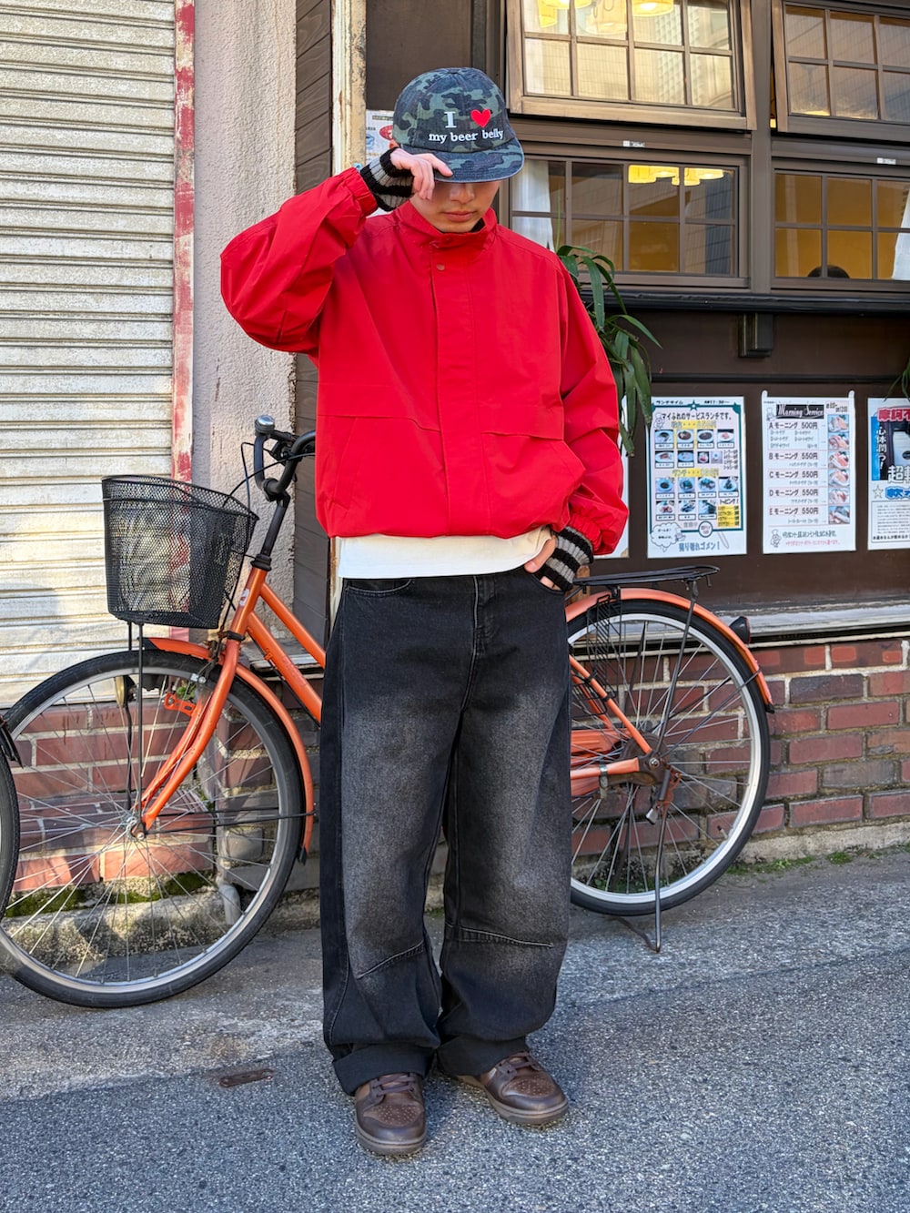 ブラウン系のスニーカー、レッド系のナイロンジャケット、ブラック系のデニムパンツを着用したメンズの冬コーディネートの2枚目の写真