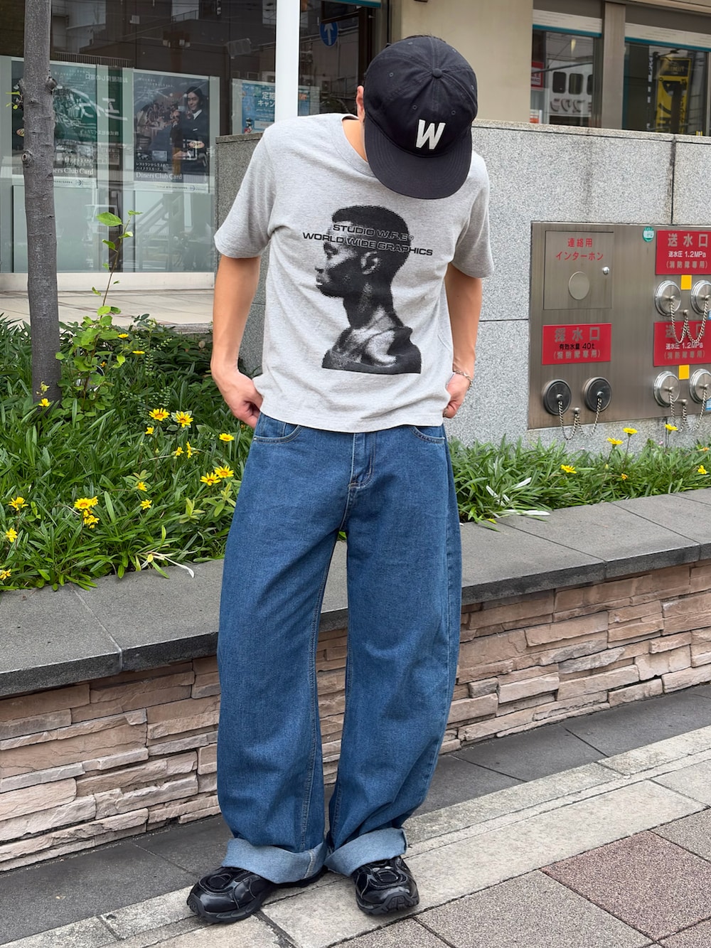 グレー系のTシャツ/カットソー、ブルー系のデニムパンツ、ブラック系のスニーカーを着用したメンズの夏コーディネートの2枚目の写真