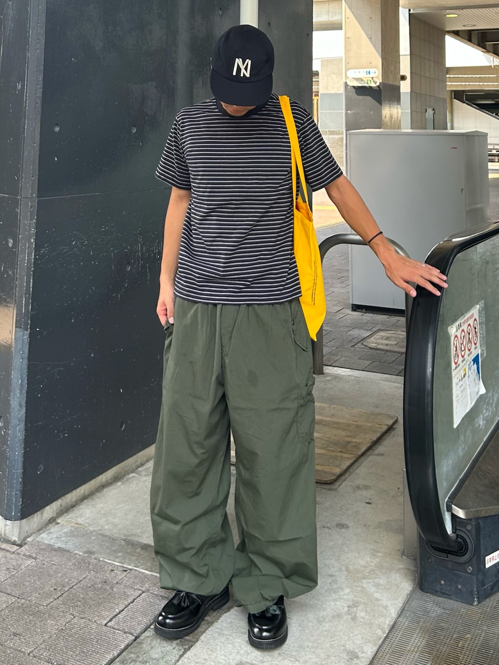 グリーン系のカーゴパンツ、ブラック系のローファー、ブラック系のTシャツ/カットソーを着用したメンズの秋コーディネートの2枚目の写真