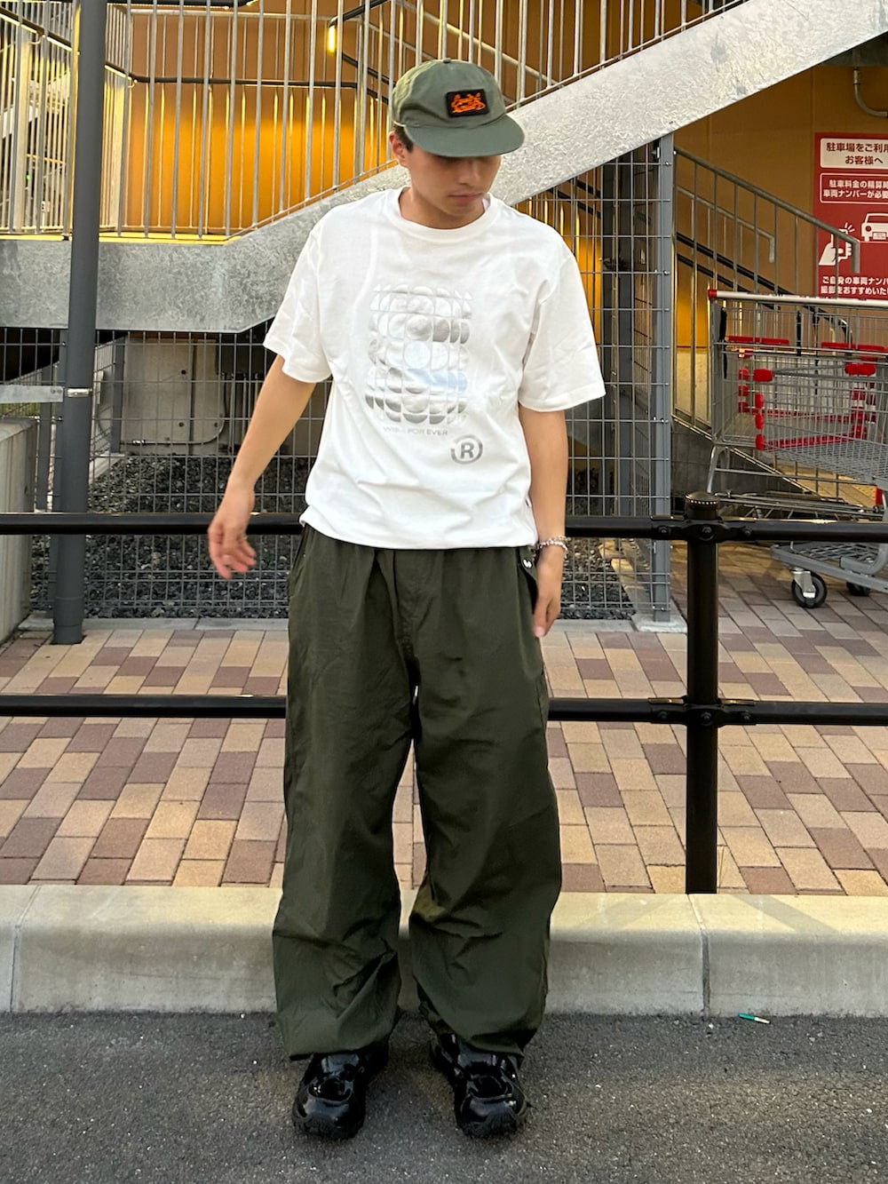 グリーン系のカーゴパンツ、ホワイト系のTシャツ/カットソー、ブラック系のスニーカーを着用したメンズの夏コーディネートの2枚目の写真