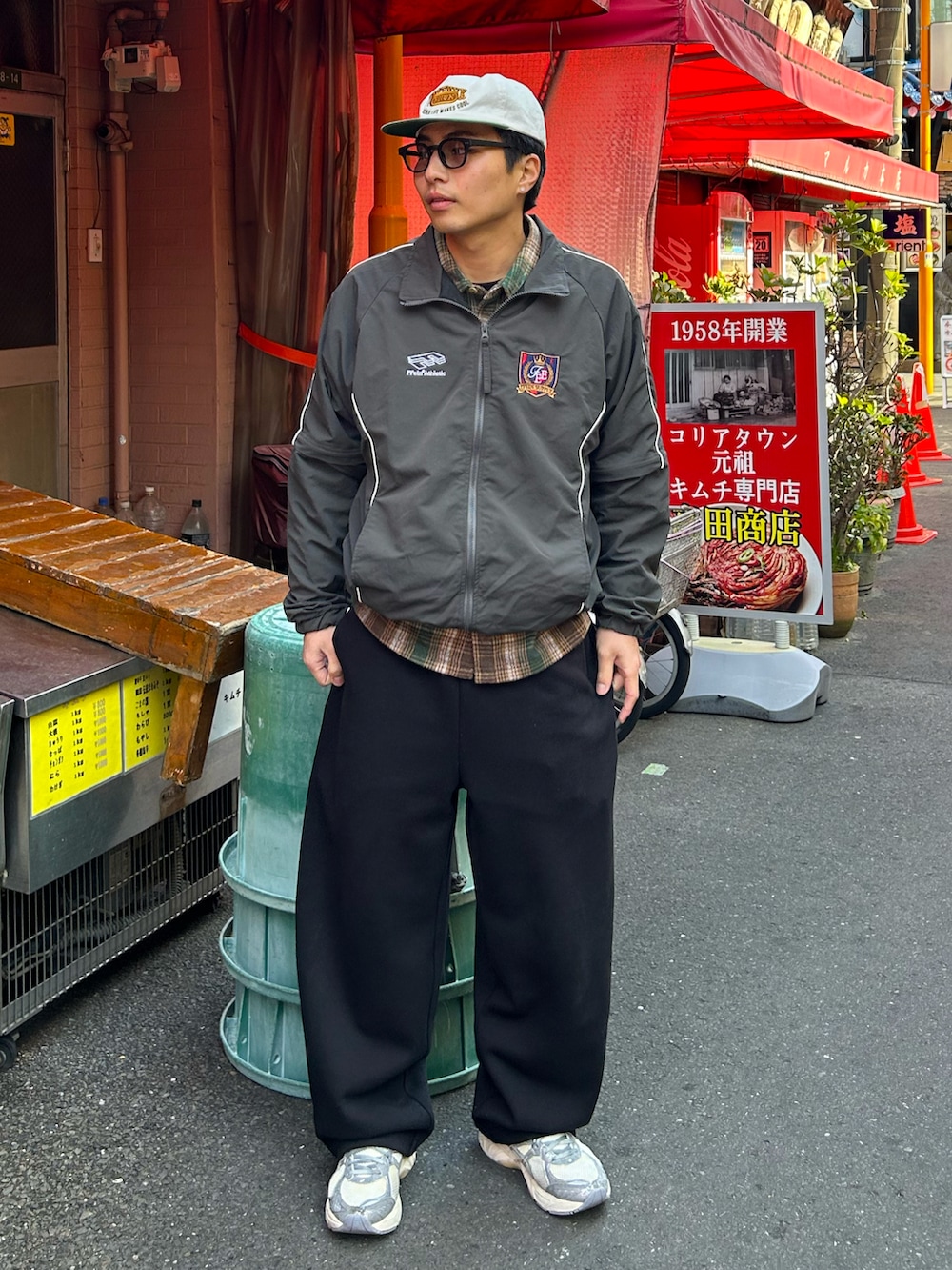 グレー系のナイロンジャケット、ブラック系のスウェットパンツ、シルバー系のスニーカーを着用したメンズの春コーディネートの2枚目の写真