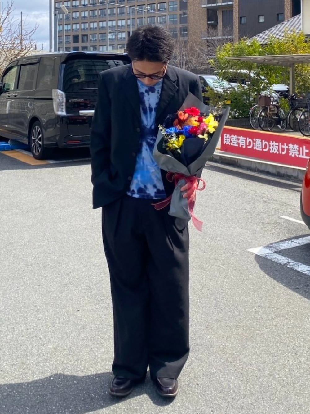 ブラック系のスラックス、ブラウン系のローファー、ブラック系のジャケット/アウターを着用したメンズの春コーディネートの2枚目の写真