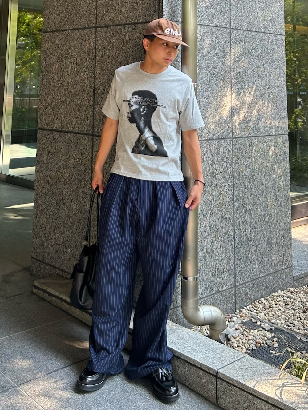 ブルー系のスラックス、グレー系のTシャツ/カットソー、ブラック系のボストンバッグを着用したメンズの秋コーディネートの2枚目の写真