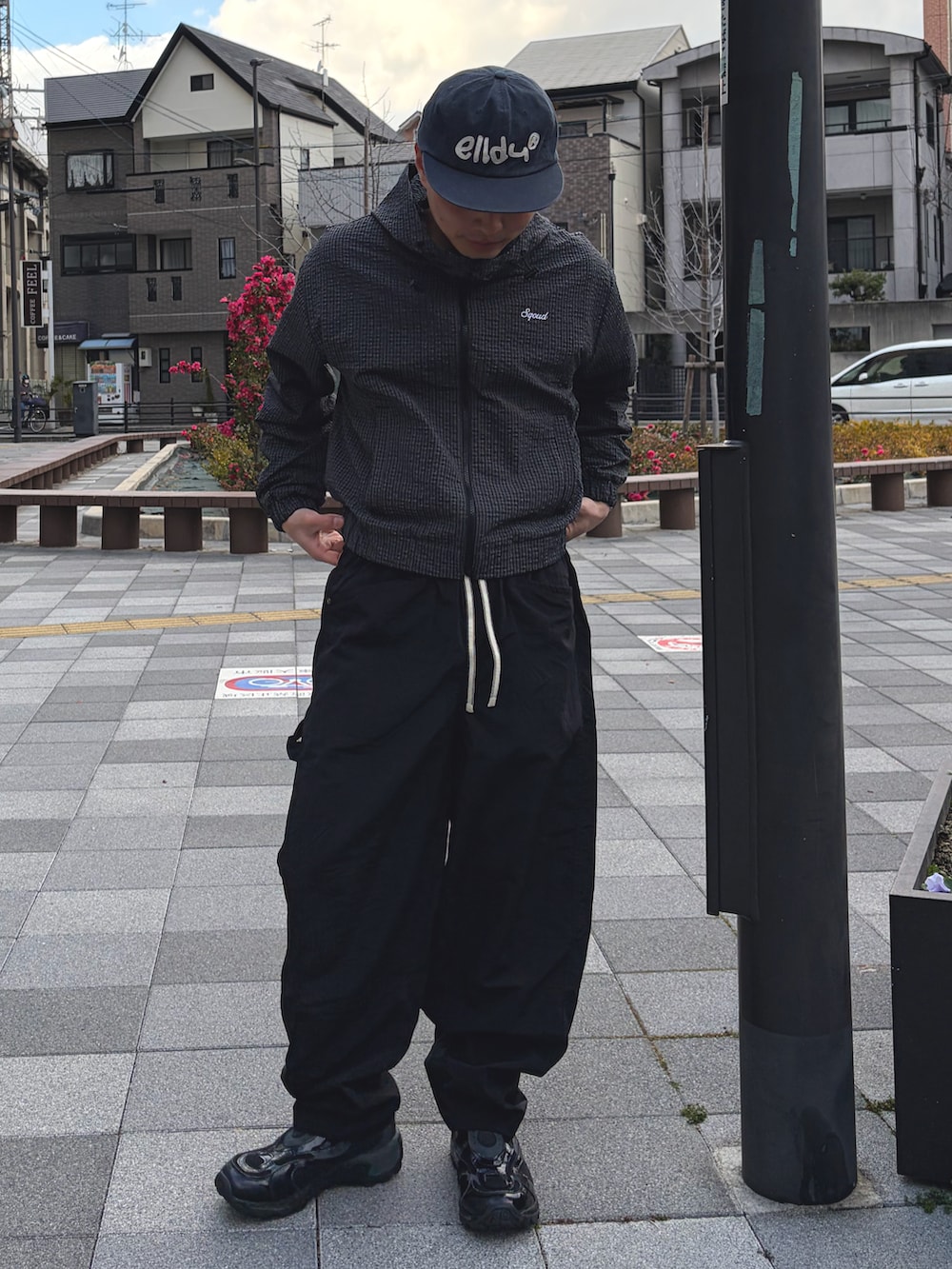 ブラック系のナイロンジャケット、ブラック系のその他パンツ、ブラック系のスニーカーを着用したメンズの春コーディネートの2枚目の写真