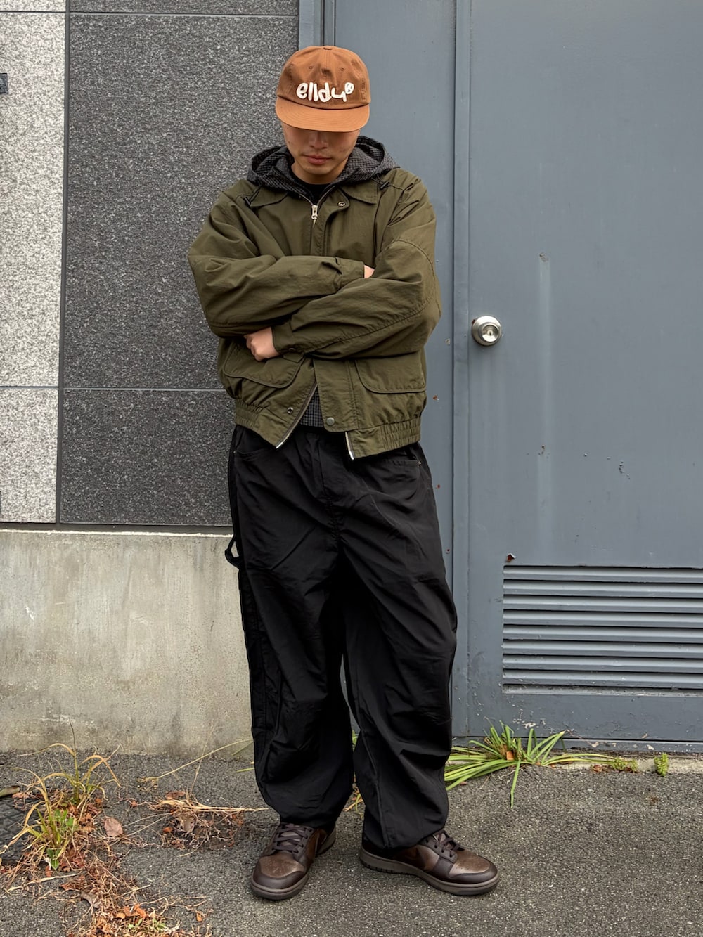 ブラウン系のスニーカー、グリーン系のテーラードジャケット、ブラック系のその他パンツを着用したメンズの春コーディネートの2枚目の写真