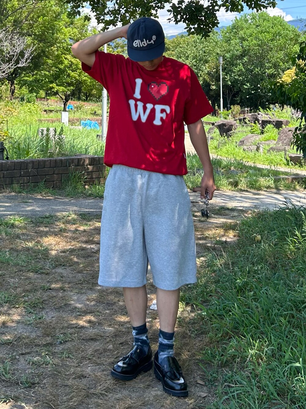 レッド系のTシャツ/カットソー、ブラック系のローファー、グレー系のスウェットパンツを着用したメンズの夏コーディネートの2枚目の写真