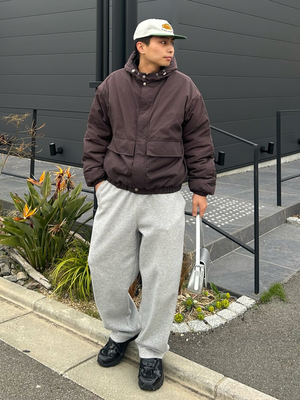 ブラウン系のダウンジャケット/コート、グレー系のスウェットパンツ、ブラック系のスニーカーを着用したメンズの春コーディネートの2枚目の写真