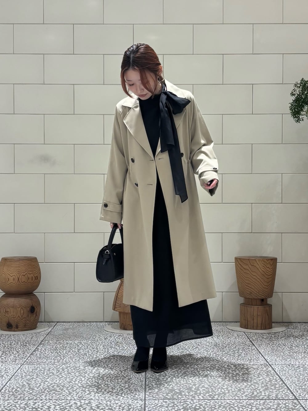 ブラック系のワンピース、ベージュ系のトレンチコート、ブラック系のパンプスを着用したレディースの冬コーディネートの3枚目の写真