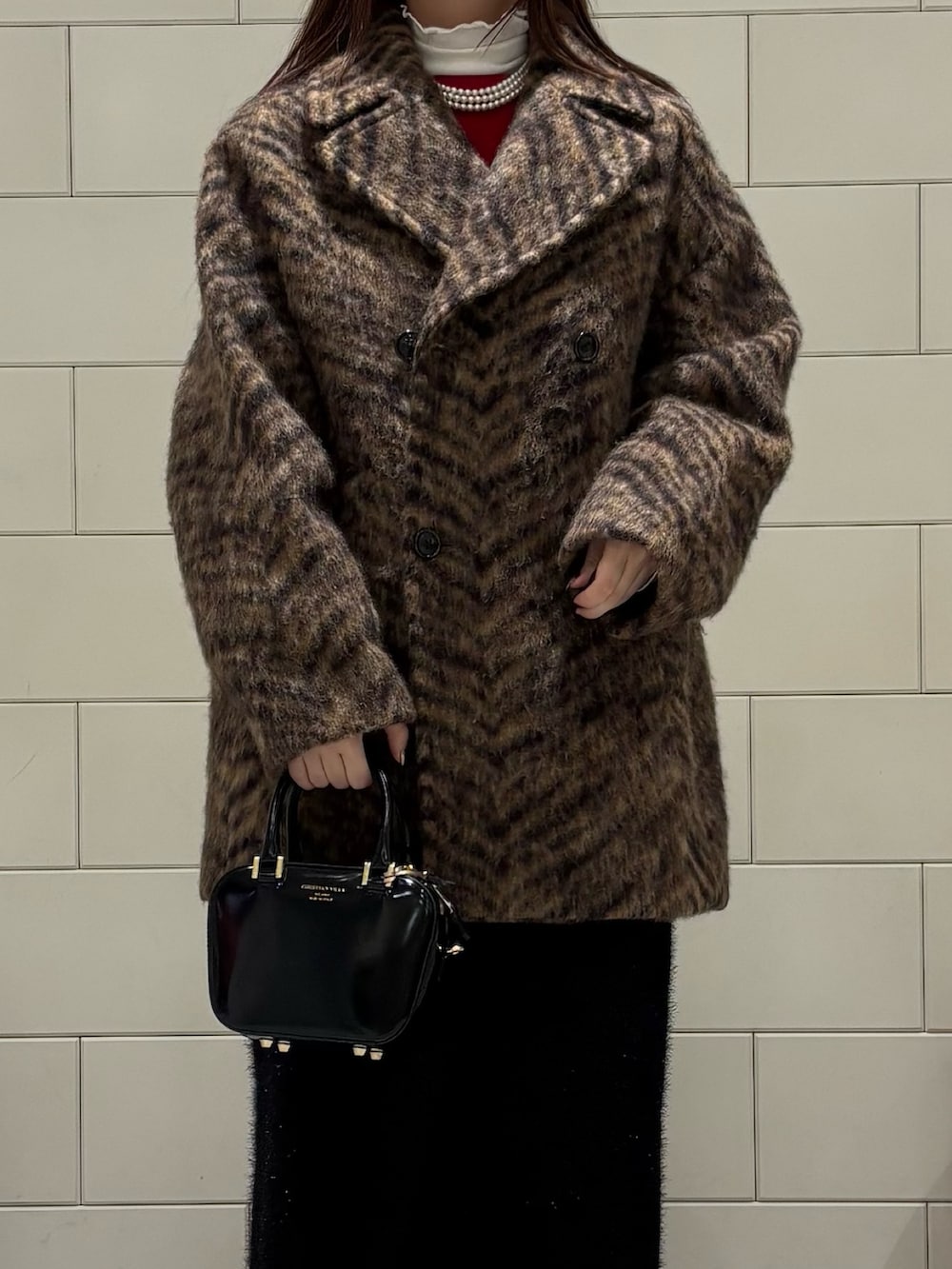 ホワイト系のTシャツ/カットソー、レッド系のニット/セーター、ベージュ系のピーコートを着用したレディースの秋コーディネートの4枚目の写真