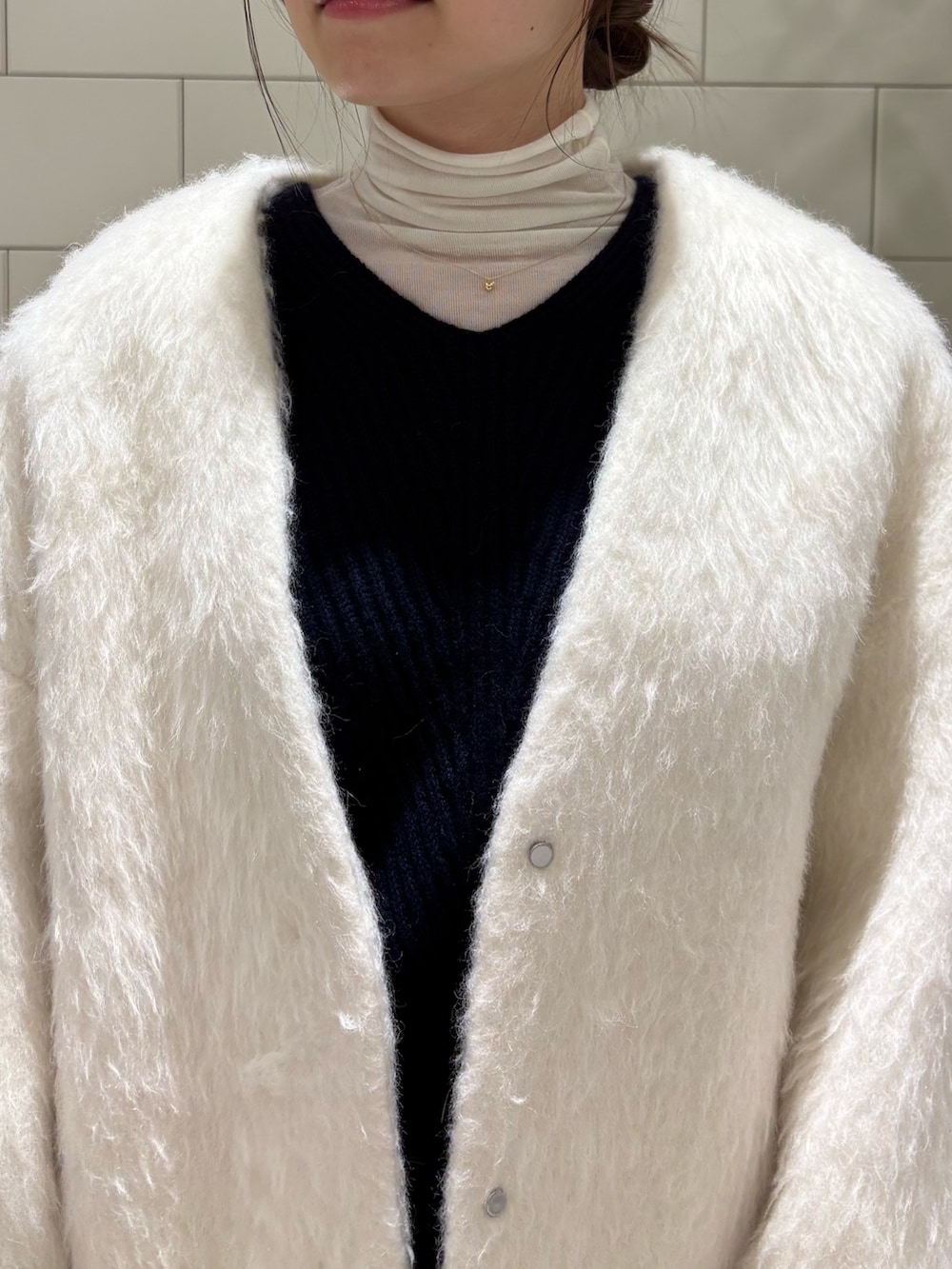 ブルー系のニット/セーター、ホワイト系のノーカラージャケット、ホワイト系のTシャツ/カットソーを着用したレディースの冬コーディネートの3枚目の写真