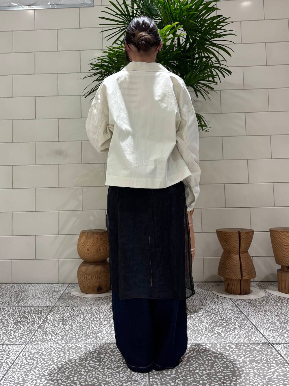 ホワイト系のスニーカー、ブラック系のワンピース、ブルー系のデニムパンツを着用したレディースの冬コーディネートの3枚目の写真