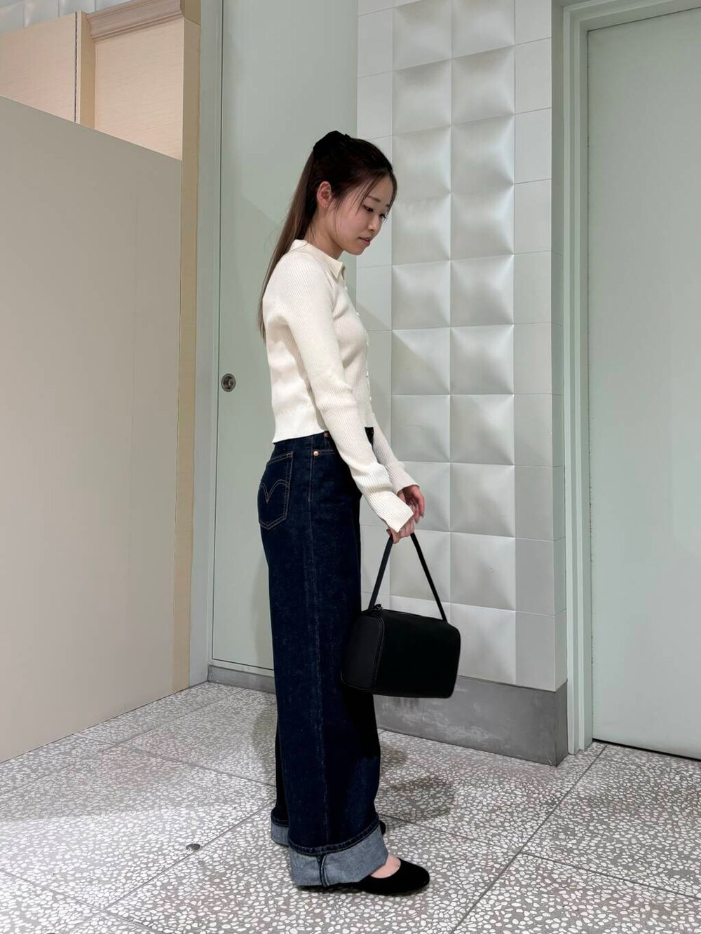 ブルー系のデニムパンツ、オレンジ系のタンクトップ、ブラック系のハンドバッグを着用したレディースの夏コーディネートの4枚目の写真