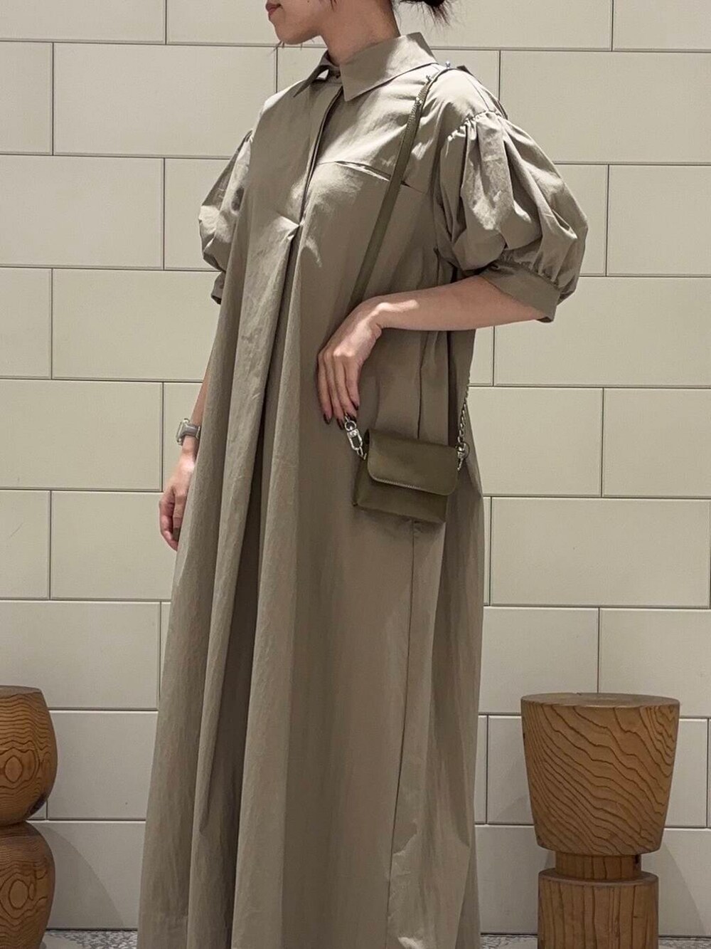 グリーン系のショルダーバッグ、ベージュ系のワンピースを着用したレディースの夏コーディネートの3枚目の写真