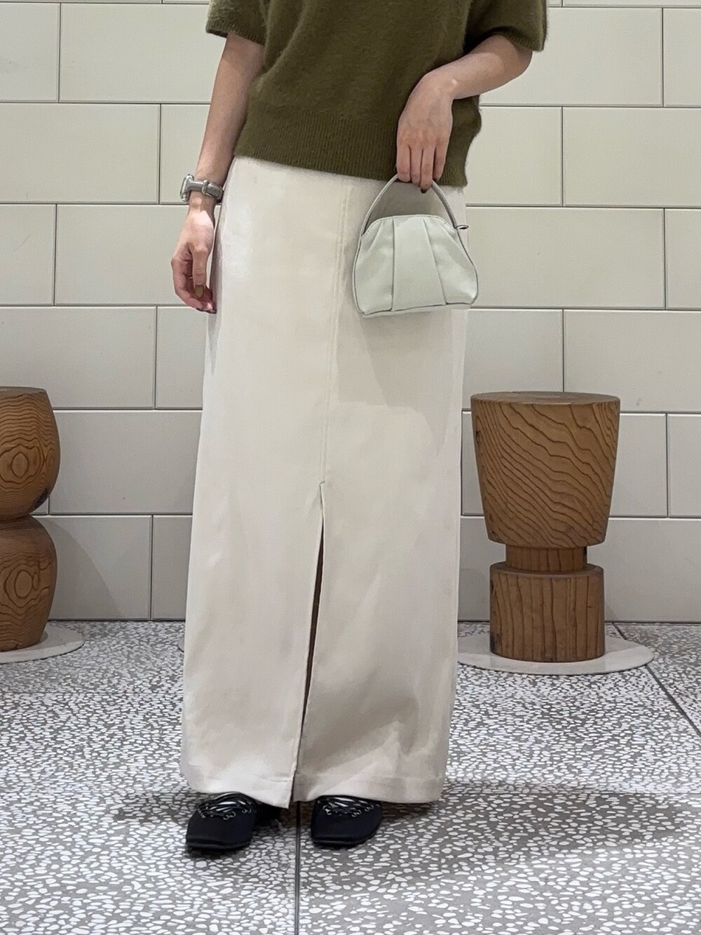 グリーン系のニット/セーター、ホワイト系のスカート、ホワイト系のハンドバッグを着用したレディースの夏コーディネートの3枚目の写真