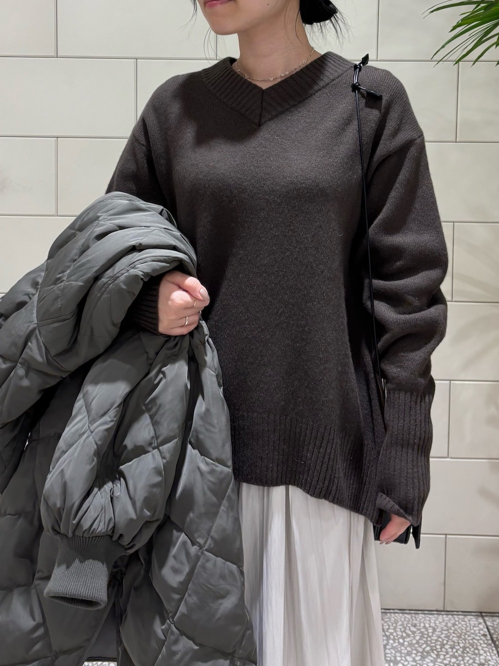 ブラウン系のニット/セーター、グレー系のダウンジャケット/コート、ブラック系のショルダーバッグを着用したレディースの冬コーディネートの3枚目の写真