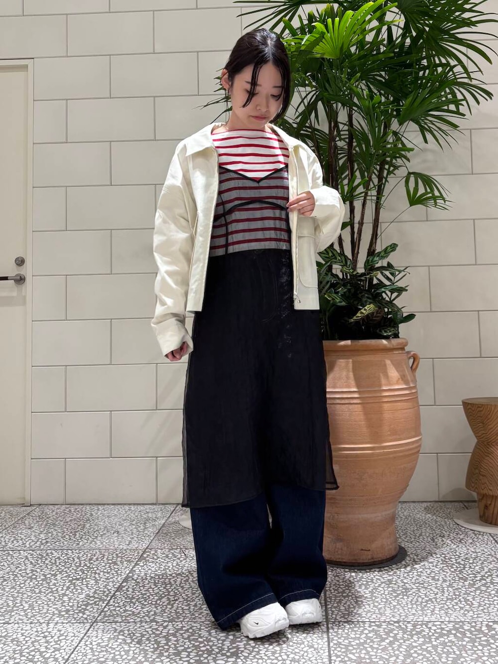 ホワイト系のスニーカー、ブラック系のワンピース、ブルー系のデニムパンツを着用したレディースの冬コーディネートの2枚目の写真