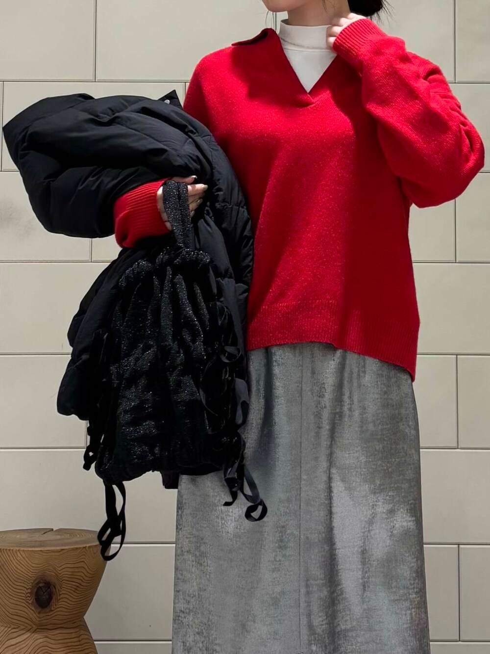 ブラック系のダウンジャケット/コート、シルバー系のスカート、レッド系のニット/セーターを着用したレディースの冬コーディネートの7枚目の写真