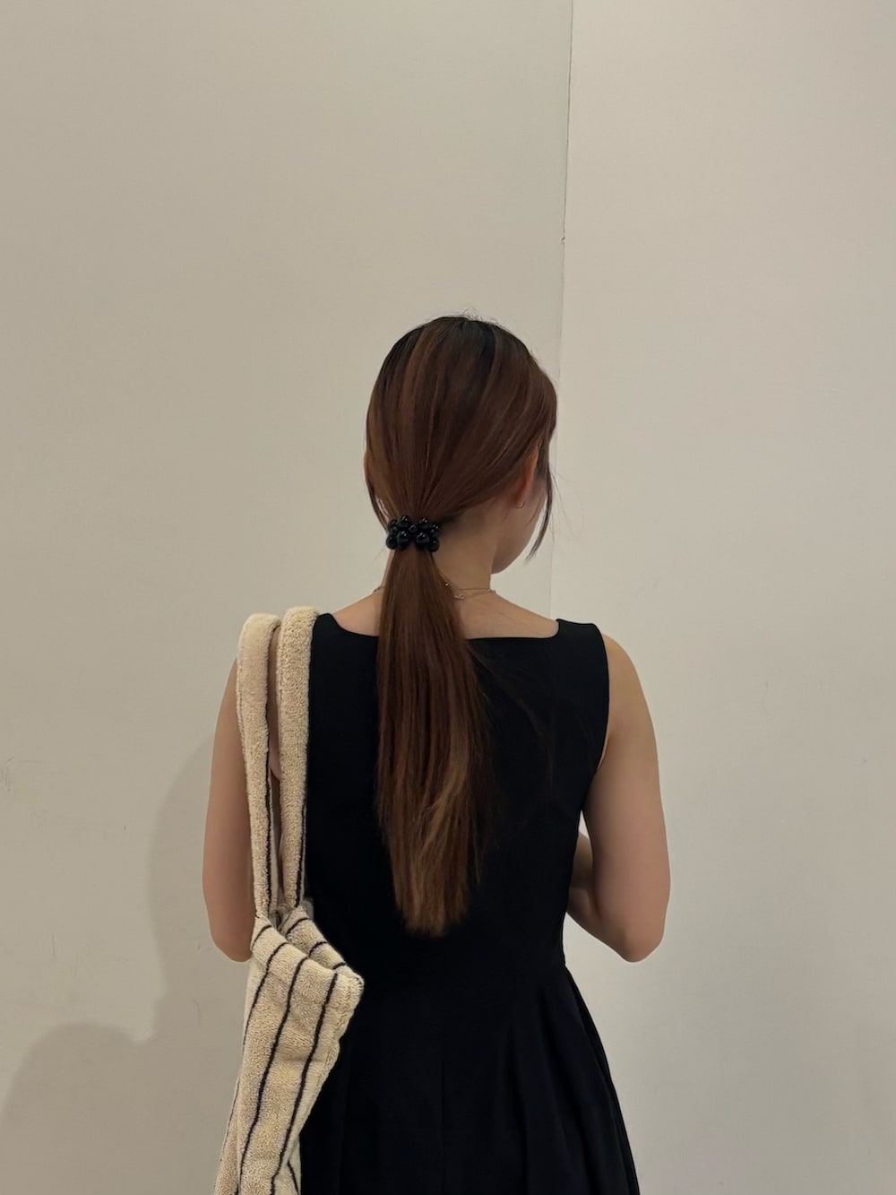 ブラック系のワンピース、ホワイト系のトートバッグ、ブラック系のヘアゴムを着用したレディースの夏コーディネートの4枚目の写真