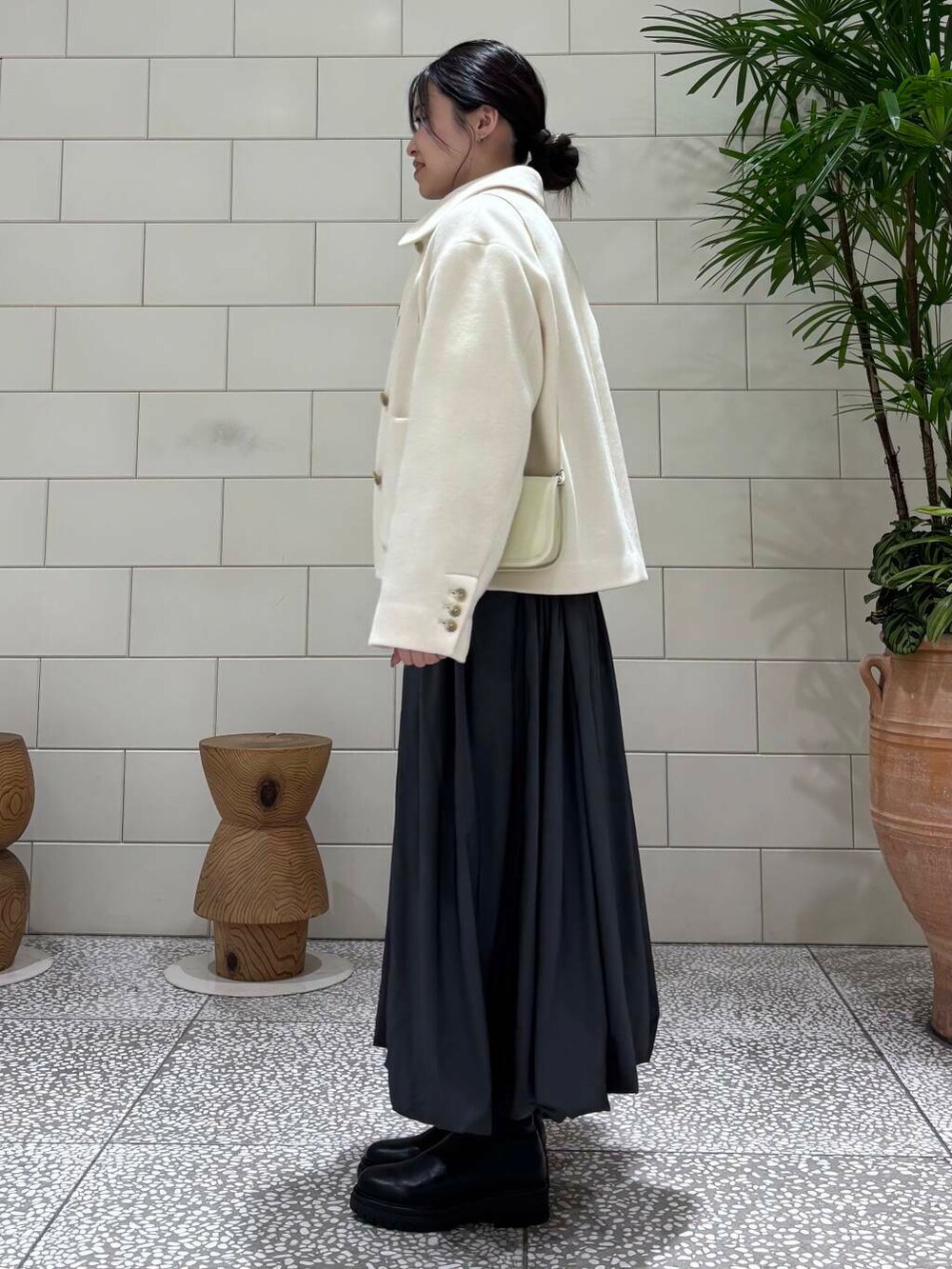 ブラック系のブーツ、ホワイト系のその他アウター、グレー系のカーディガン/ボレロを着用したレディースの冬コーディネートの3枚目の写真