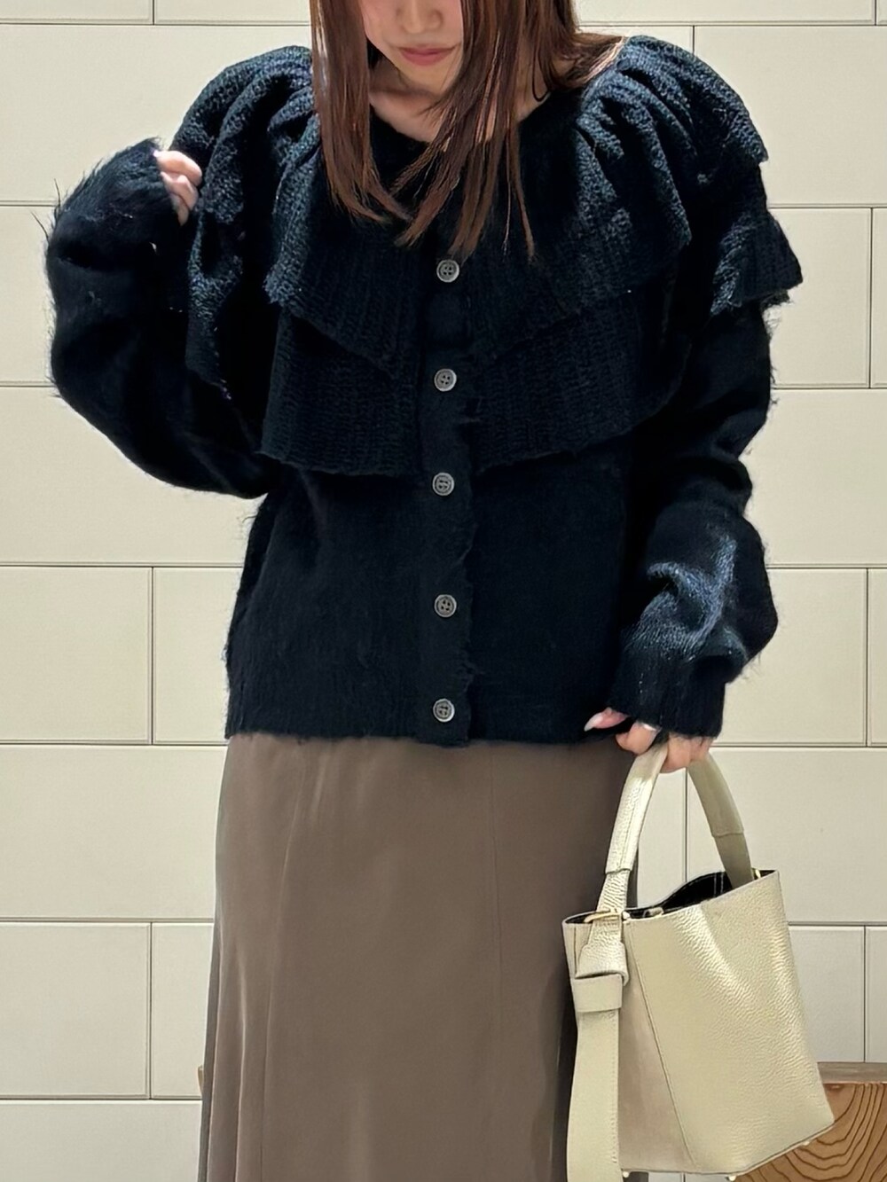 ブラウン系のスカート、ブラック系のブーツ、グリーン系のニット/セーターを着用したレディースの秋コーディネートの3枚目の写真