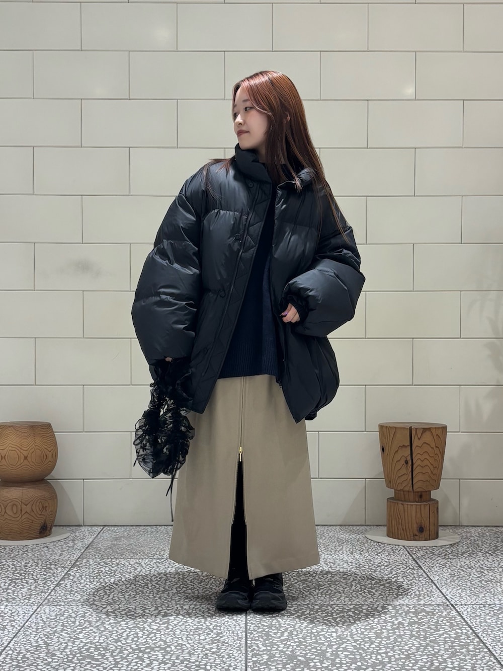 ブラック系のダウンジャケット/コート、ブラック系のニット/セーター、ベージュ系のスカートを着用したレディースの冬コーディネートの2枚目の写真