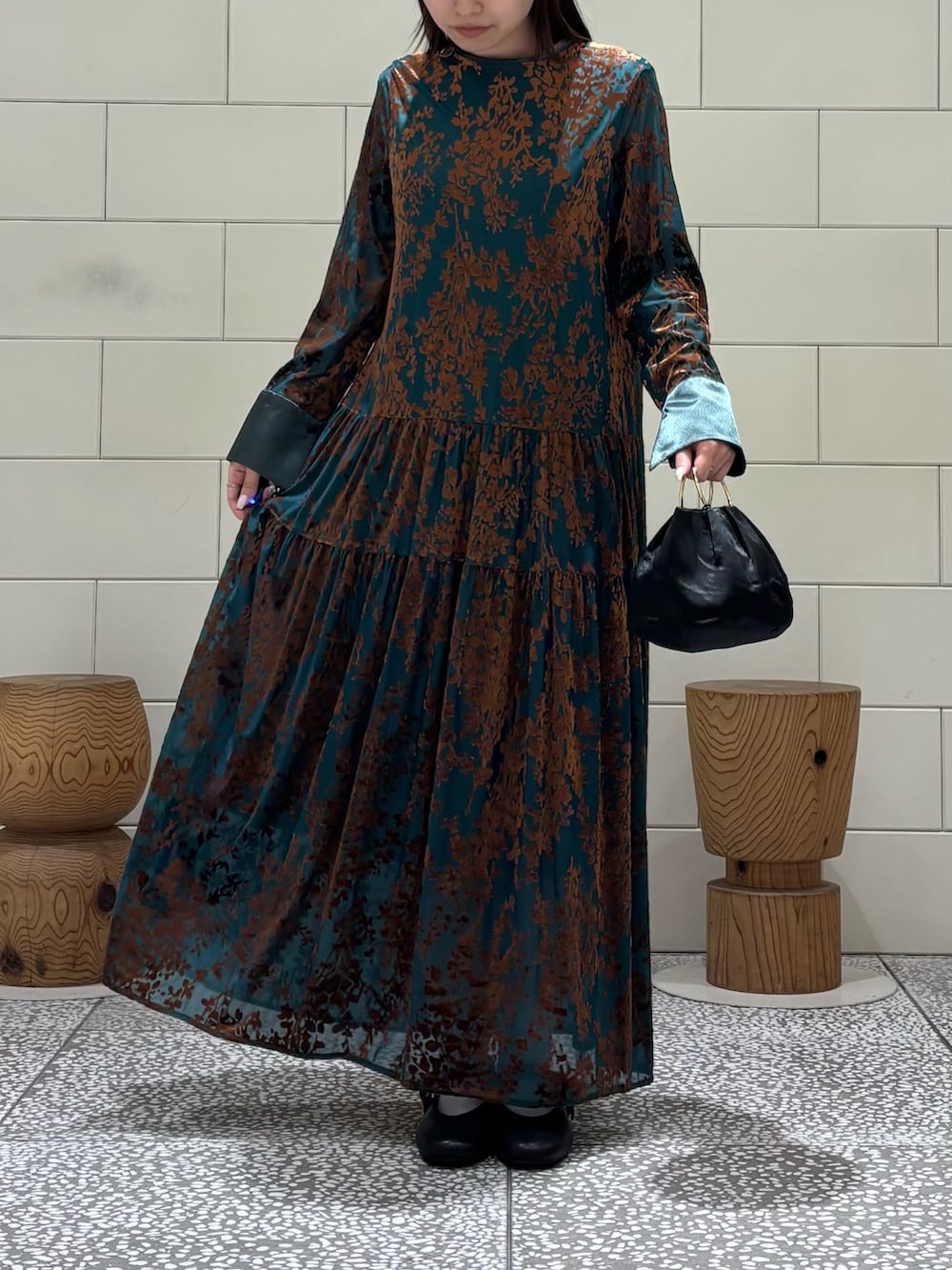 グリーン系のワンピース、ブラック系のハンドバッグ、ブラック系のバレエシューズを着用したレディースの秋コーディネートの3枚目の写真