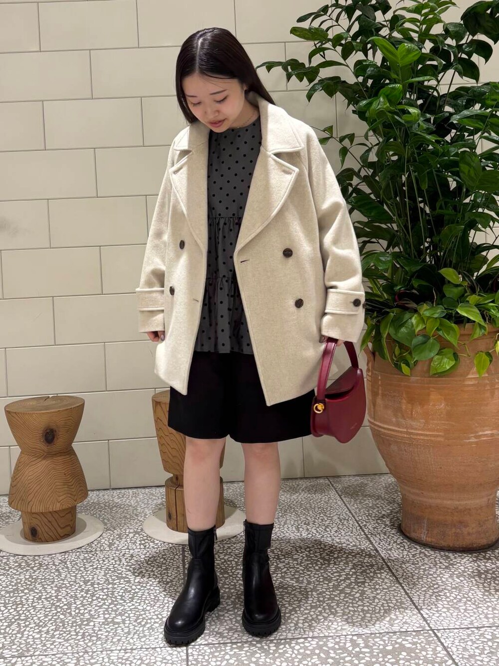 ベージュ系のピーコート、ブラック系のブーツ、ブラック系のその他パンツを着用したレディースの秋コーディネートの2枚目の写真