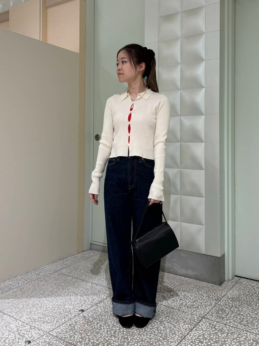 ブルー系のデニムパンツ、オレンジ系のタンクトップ、ブラック系のハンドバッグを着用したレディースの夏コーディネートの2枚目の写真