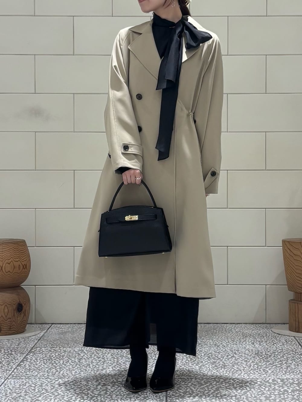 ブラック系のワンピース、ベージュ系のトレンチコート、ブラック系のパンプスを着用したレディースの冬コーディネートの4枚目の写真
