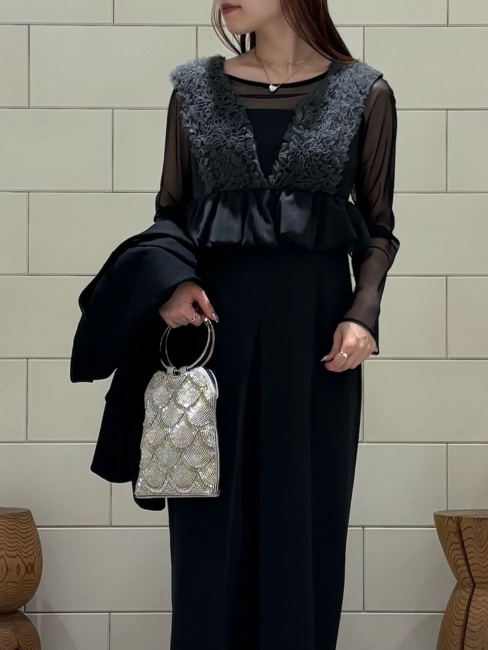 グレー系のドレス、ブラック系のテーラードジャケット、シルバー系のハンドバッグを着用したレディースの春コーディネートの4枚目の写真