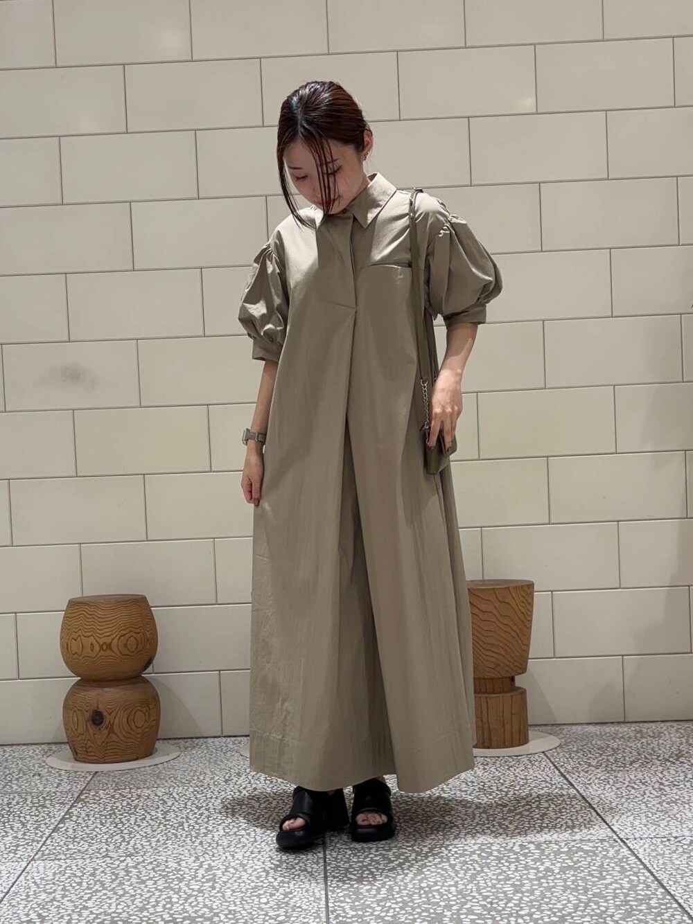 グリーン系のショルダーバッグ、ベージュ系のワンピースを着用したレディースの夏コーディネートの2枚目の写真