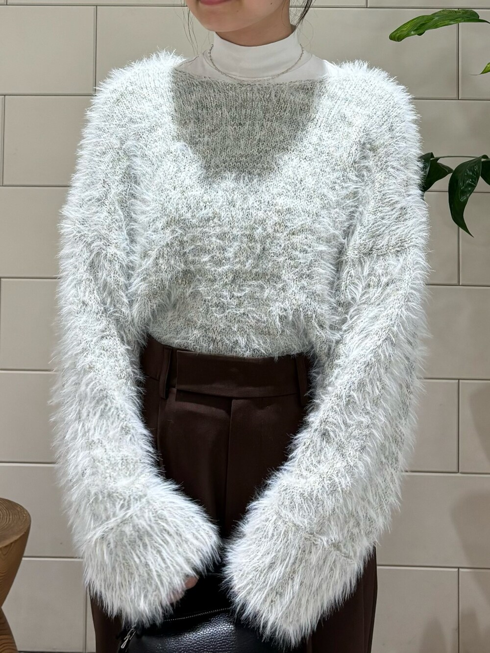 グレー系のニット/セーター、ブラック系のショルダーバッグ、ブラック系のブーツを着用したレディースの秋コーディネートの5枚目の写真