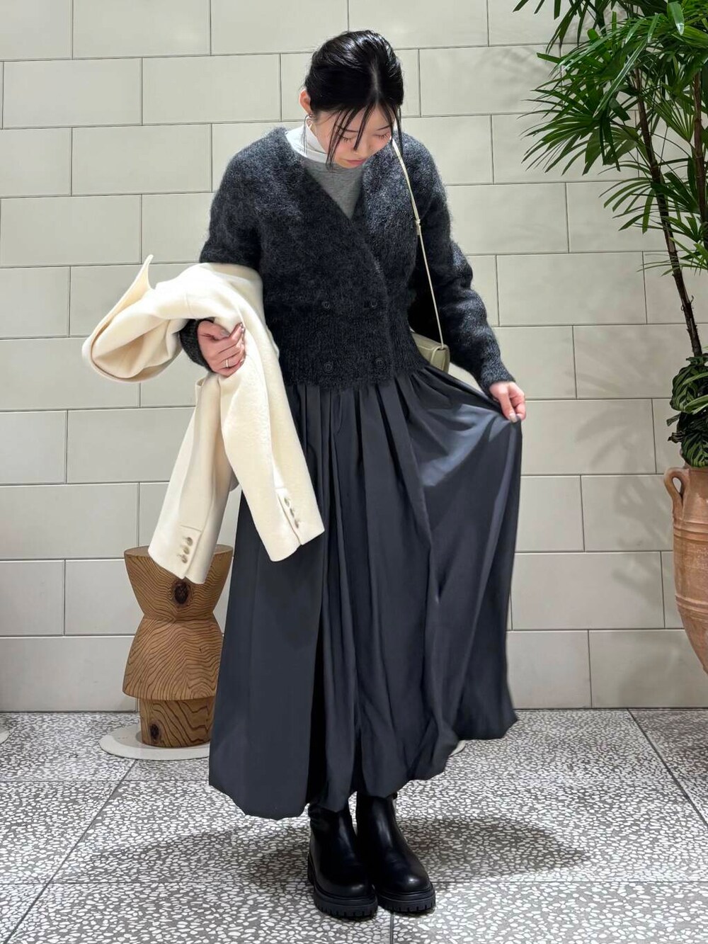 ブラック系のブーツ、ホワイト系のその他アウター、グレー系のカーディガン/ボレロを着用したレディースの冬コーディネートの4枚目の写真