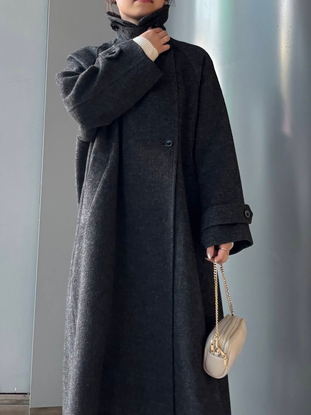 ブラック系のステンカラーコート、ホワイト系のショルダーバッグ、ブラウン系のスカートを着用したレディースの冬コーディネートの7枚目の写真