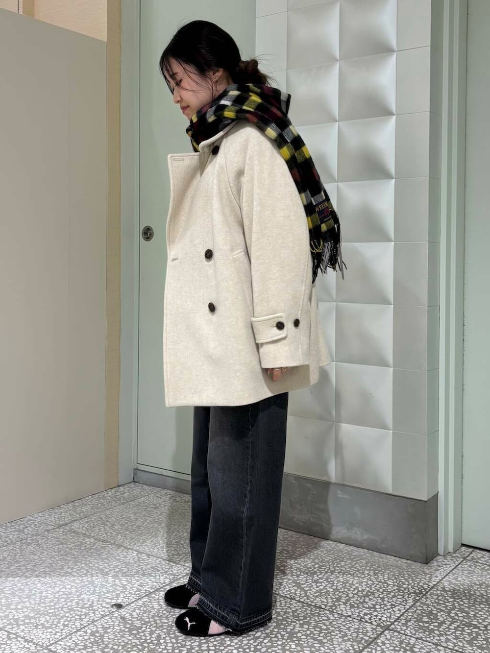 ベージュ系のピーコート、ホワイト系のTシャツ/カットソー、ブラック系のデニムパンツを着用したレディースの冬コーディネートの3枚目の写真