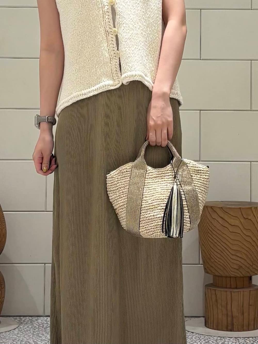 ゴールド系のかごバッグ、ホワイト系のベスト、ベージュ系のスカートを着用したレディースの夏コーディネートの5枚目の写真