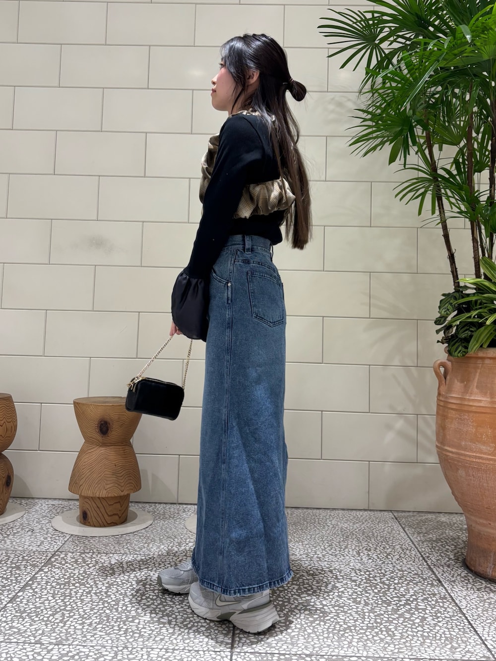 ブラック系のTシャツ/カットソー、ブルー系のスカート、ブラック系のショルダーバッグを着用したレディースの冬コーディネートの2枚目の写真