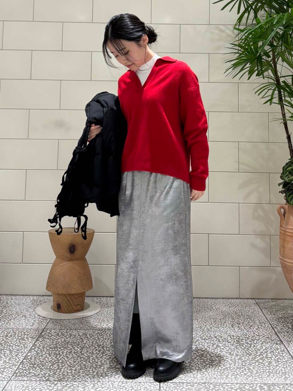 ブラック系のダウンジャケット/コート、シルバー系のスカート、レッド系のニット/セーターを着用したレディースの冬コーディネートの2枚目の写真