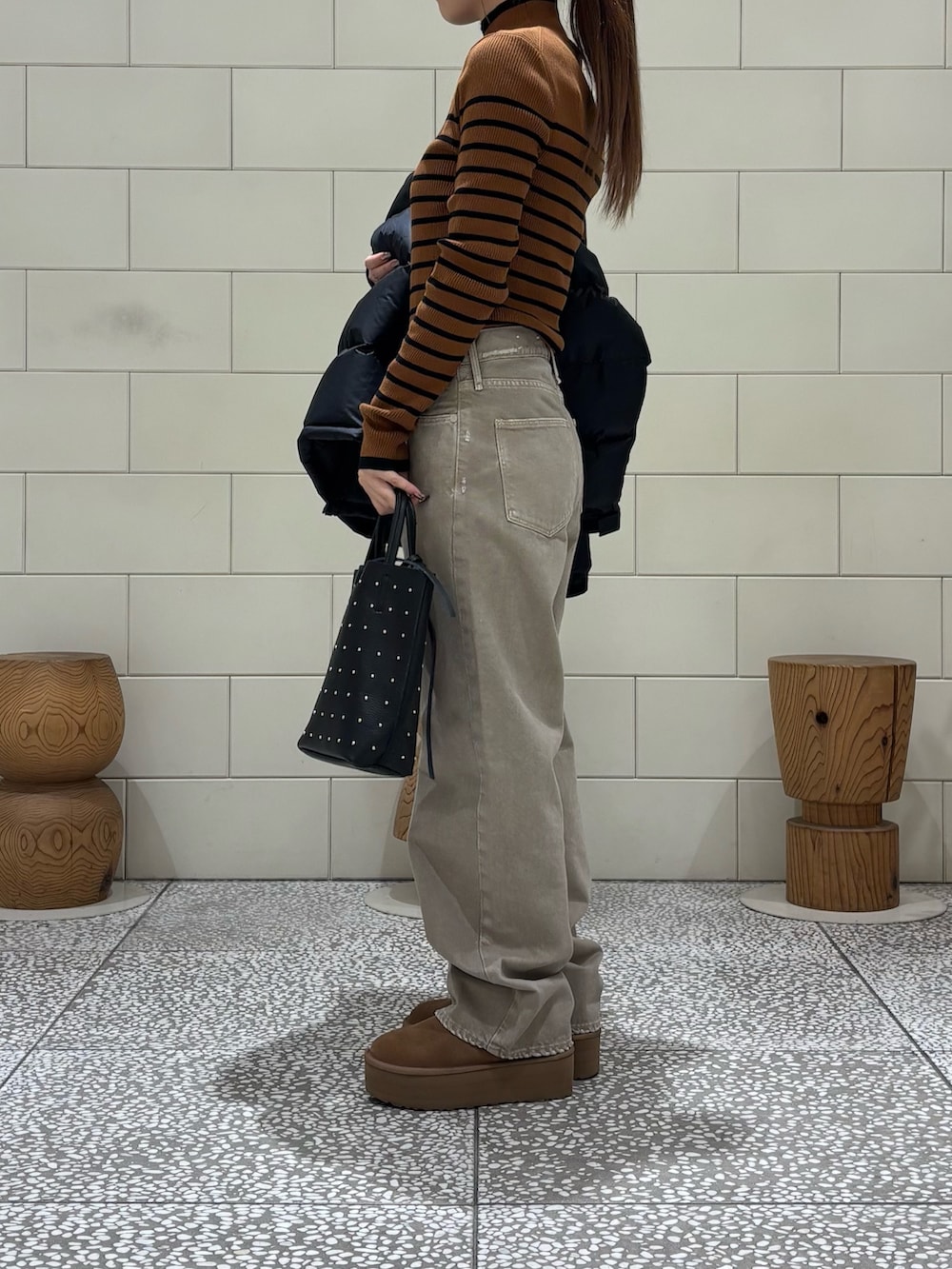 ブラウン系のニット/セーター、ブラック系のダウンジャケット/コート、ベージュ系のデニムパンツを着用したレディースの秋コーディネートの2枚目の写真