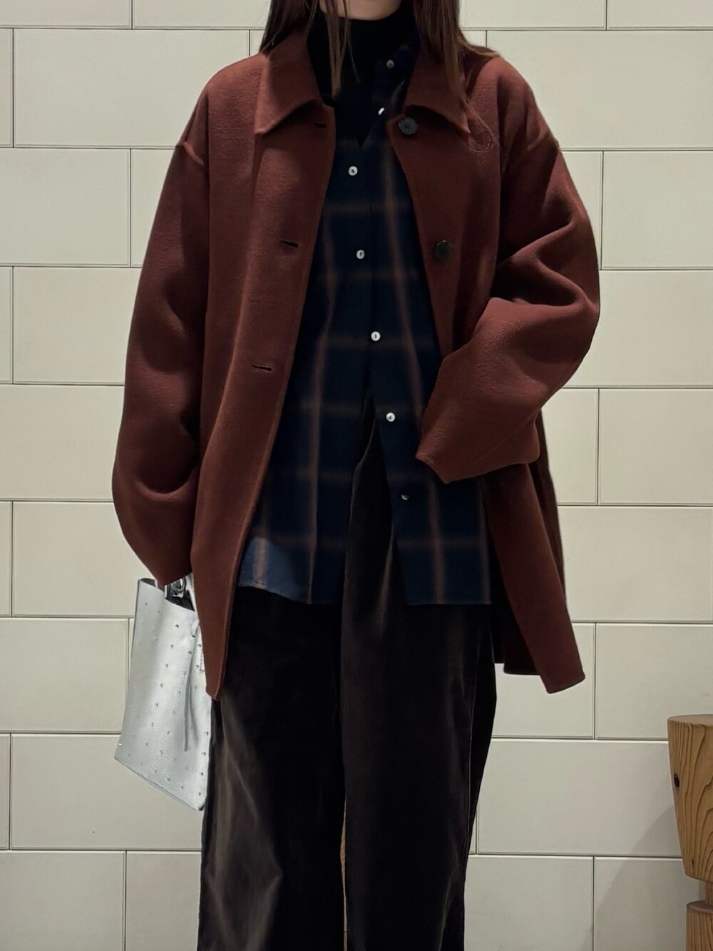 ブラック系のTシャツ/カットソー、ブラウン系のステンカラーコート、シルバー系のトートバッグを着用したレディースの冬コーディネートの5枚目の写真