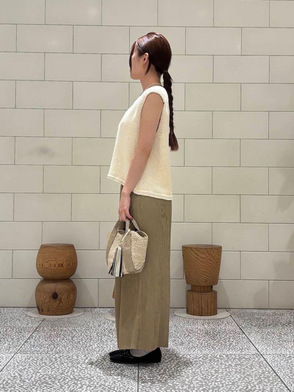 ゴールド系のかごバッグ、ホワイト系のベスト、ベージュ系のスカートを着用したレディースの夏コーディネートの2枚目の写真