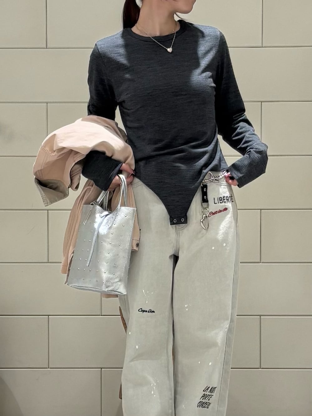 ピンク系のカバーオール、シルバー系のトートバッグ、グレー系のデニムパンツを着用したレディースの冬コーディネートの3枚目の写真