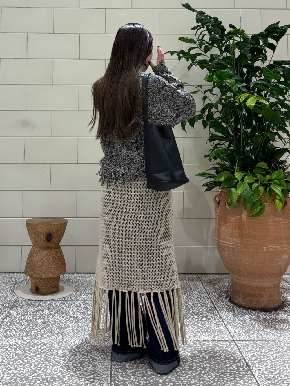 ブラック系のニット/セーター、ブルー系のデニムパンツ、ブラック系のブーツを着用したレディースの秋コーディネートの3枚目の写真