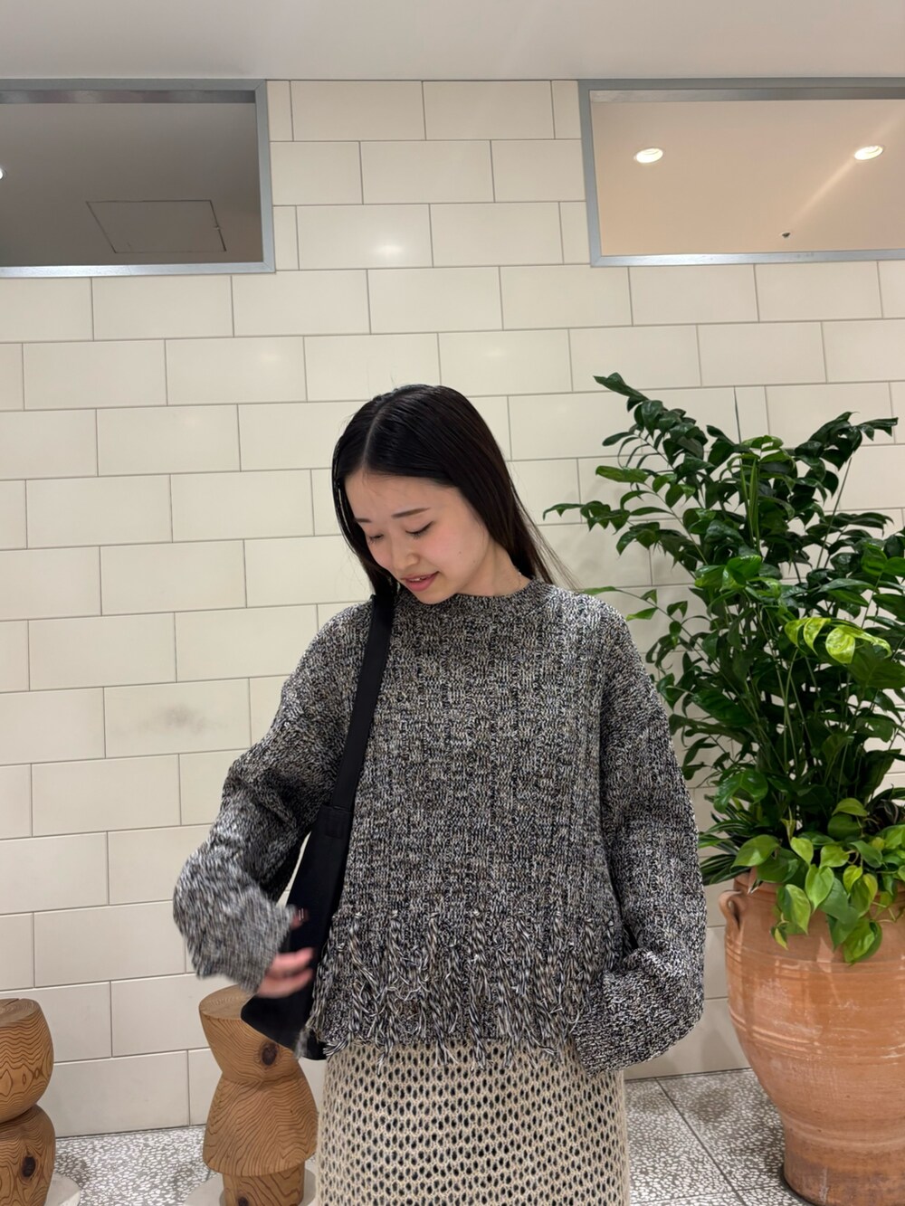 ブラック系のニット/セーター、ブルー系のデニムパンツ、ブラック系のブーツを着用したレディースの秋コーディネートの4枚目の写真