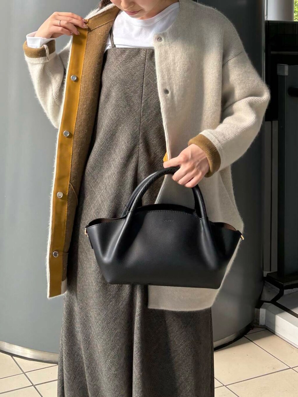 ホワイト系のTシャツ/カットソー、ブラック系のブーツ、グレー系のカーディガン/ボレロを着用したレディースの秋コーディネートの6枚目の写真